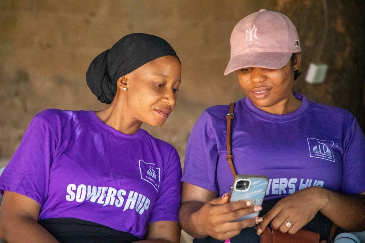 Two SowersHub volunteers in branded shirts planning together at an outreach