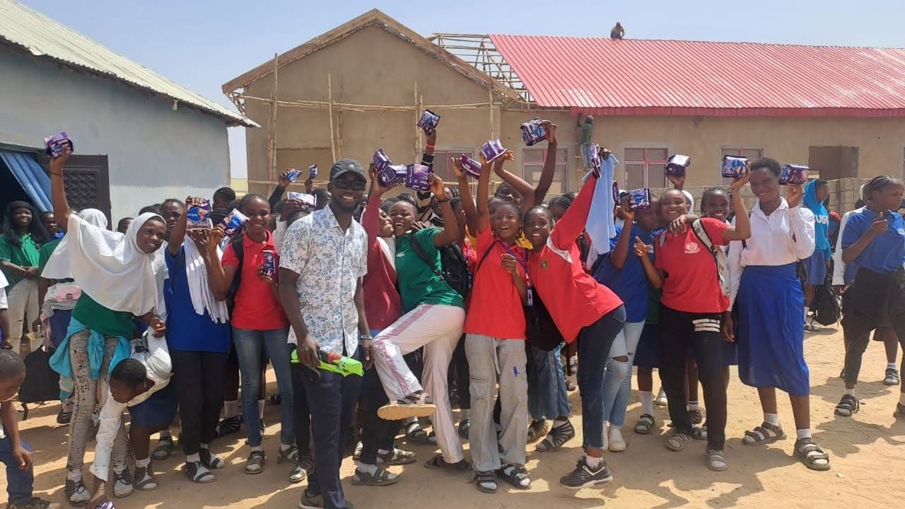 Schoolgirls cheering with sanitary pads held above their heads at a northern outreach