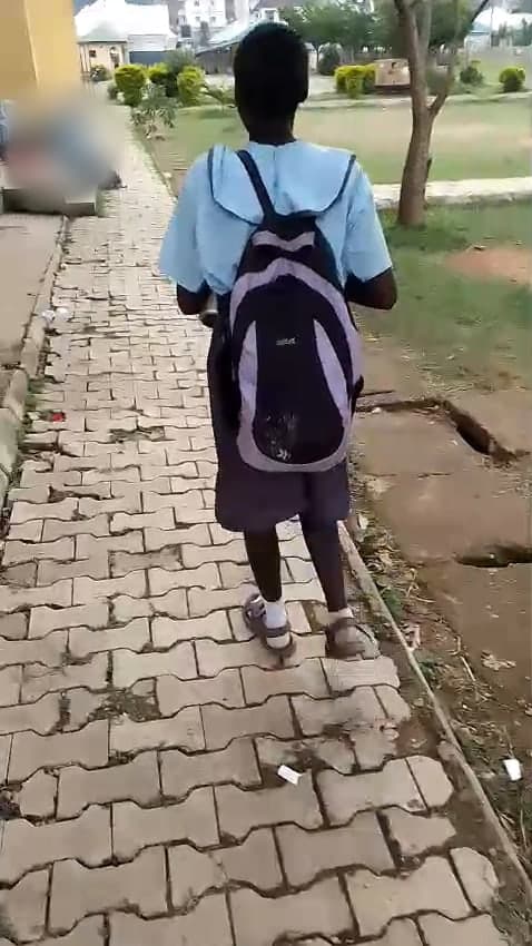 Jessica walking to class in her school uniform, carrying her school bag